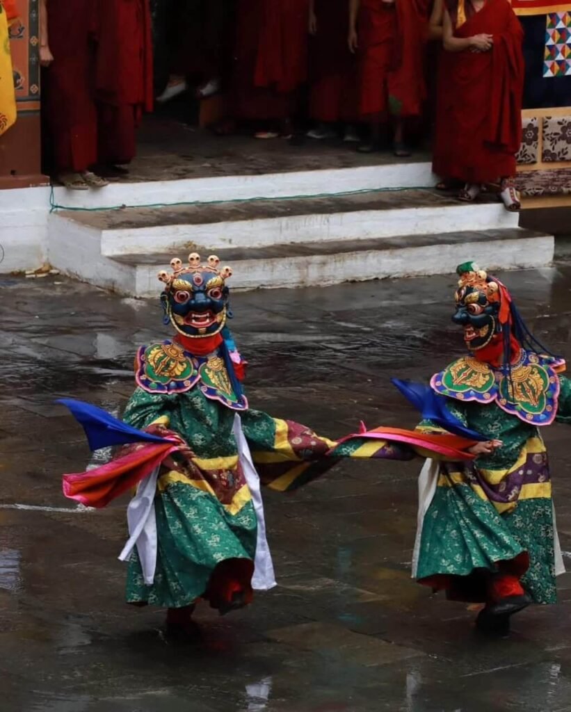 Two cham dancers in a dzong courtyard during a tshechu